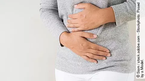 Frau hält sich mit beiden Händen den Bauch