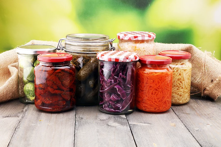Gläser mit fermentiertem Gemüse auf einem Holztisch