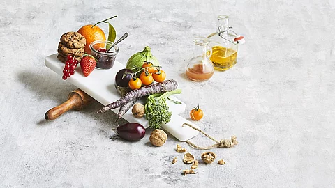 Obst, Gemüse, Marmelade, Nüsse, Cookies, Öl und Saft ästhetisch gruppiert auf weißem Untergrund
