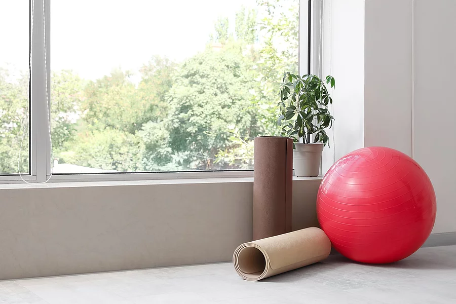 Gymnastikball und 2 Fitnessmatten neben einem Fenster