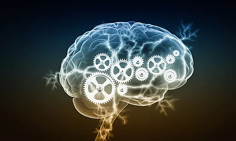Illustration: Gehirn mit ineinandergreifenden Zahnrädern und Blitzen