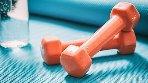 Hanteln, ein Glas Wasser auf einer Yogamatte