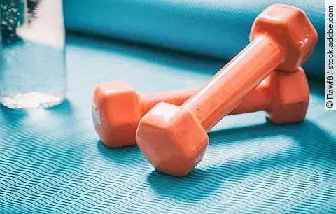 Hanteln, ein Glas Wasser auf einer Yogamatte