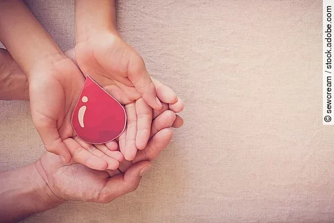 Zwei Paar Hände halten Bluttropfen aus Papier.