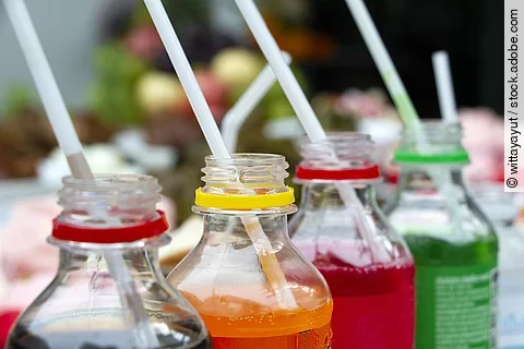4 Limonadenflaschen mit Getränken in verschiedenen Farben und Strohhalmen