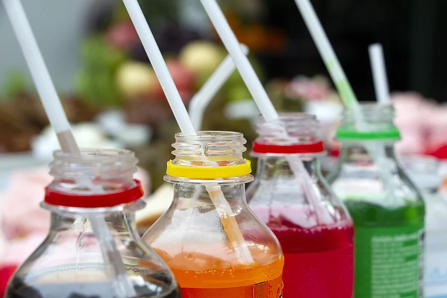 4 Limonadenflaschen mit Getränken in verschiedenen Farben und Strohhalmen 4 Limonadenflaschen mit Getränken in verschiedenen Farben und Strohhalmen