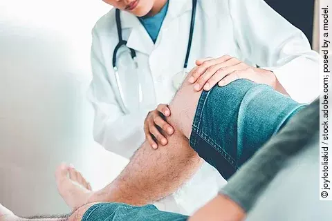 Ärztin behandelt Patienten mit Knieschmerzen.