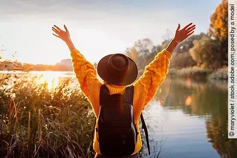Frau mit Rucksack am See, Freude