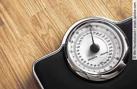 Schwarze Waage auf einem Holzboden.