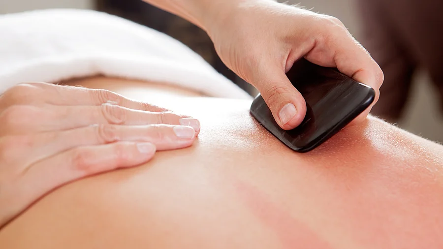 Gua-Sha-Behandlung am Rücken einer liegenden Person Gua-Sha-Behandlung am Rücken einer liegenden Person