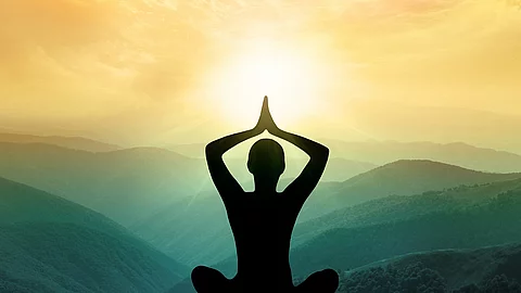 Silhouette einer Frau sitzt meditierend in den Bergen