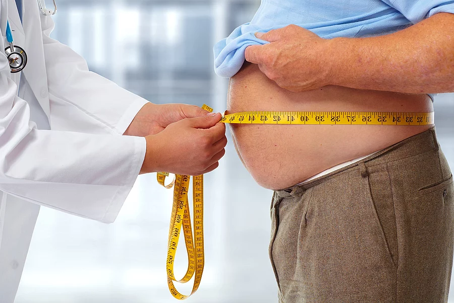 Doctor measuring obese man stomach. Arzt misst Bauchumfang bei übergewichtigem Mann