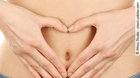 Hand formt ein Herz auf einem weiblichen Bauchnabel