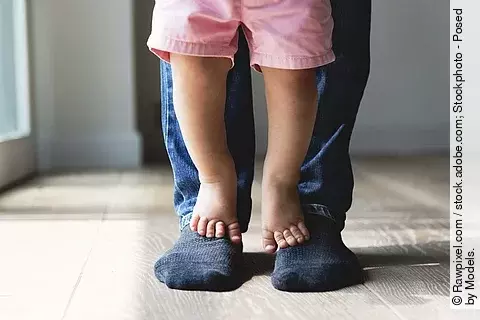 Vater und Kind stehen zusammen, Kind auf den Füßen des Vaters