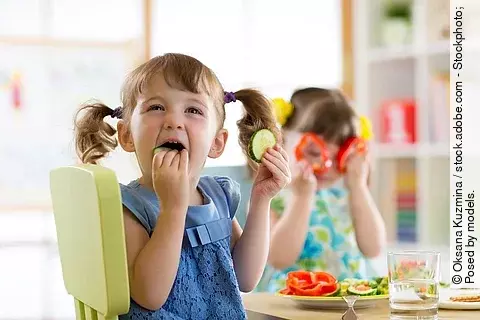 2 Mädchen am Esstisch essen Gemüse
