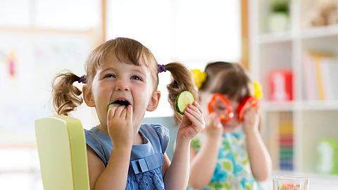 children eating vegetables in kindergarten or at home 2 Mädchen am Esstisch essen Gemüse