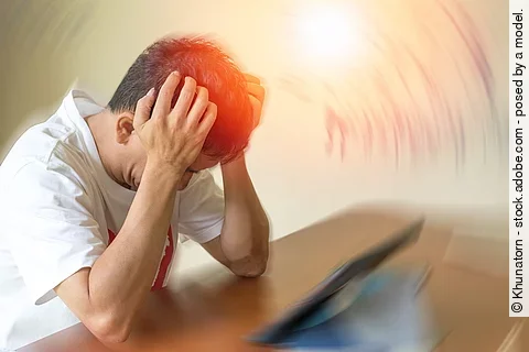 Mann mit Kopfschmerzen stützt seinen Kopf mit den Händen auf einen Tresen