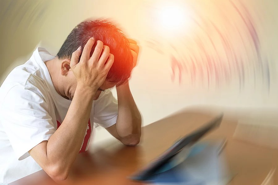 Mann mit Kopfschmerzen stützt seinen Kopf mit den Händen auf einen Tresen