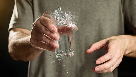 Mann hält ein Glas Wasser mit zitternder Hand