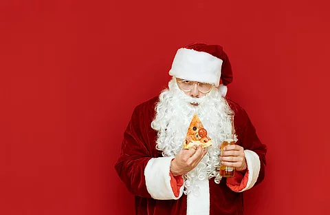 Portrait eines Nikolauses mit Pizza und Bier in der Hand