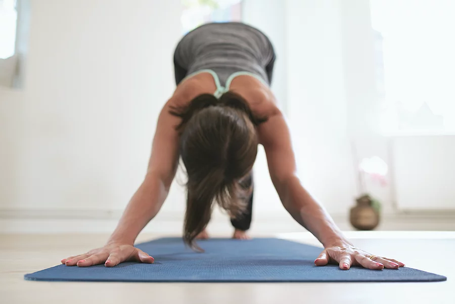 Frau macht Yoga auf einer blauen Matte.