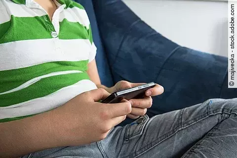 Leicht übergewichtiger Junge mit Handy