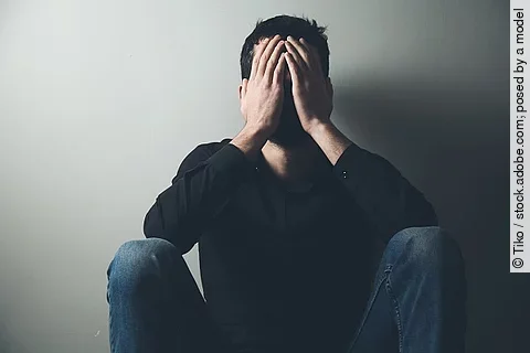 erschöpfter Mann hat die Hände vor dem Gesicht