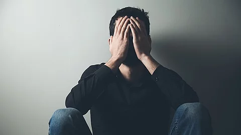 erschöpfter Mann hat die Hände vor dem Gesicht