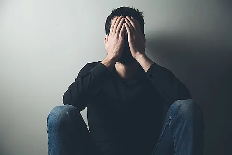 erschöpfter Mann hat die Hände vor dem Gesicht