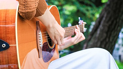 Frau spielt Gitarre in einem Park