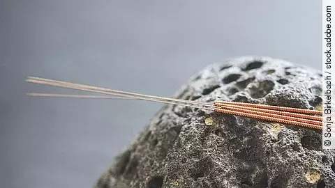 Akupunkturnadeln auf einem Lava-Stein