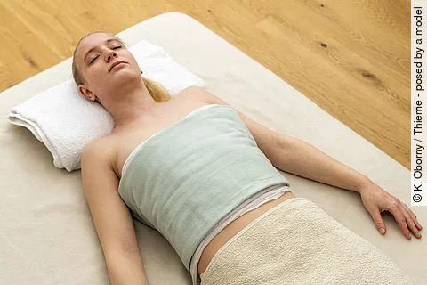 Frau liegt entspannt auf einer Decke mit einer Dampfauflage.