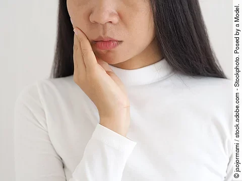 Junge Frau hält die Hand am Kiefer