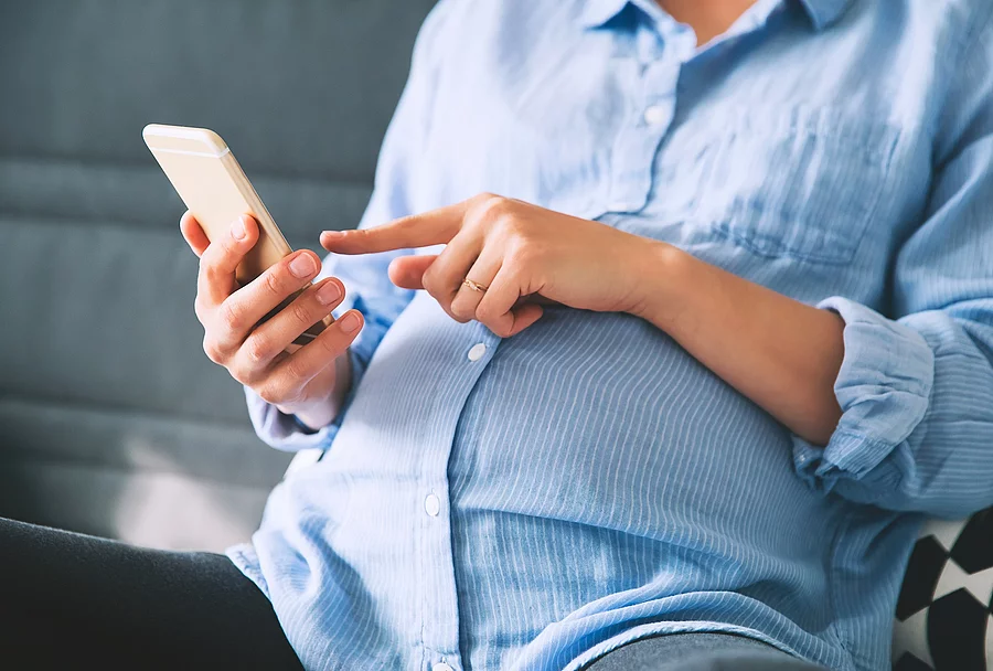 Schwangere Frau sitzt am Handy