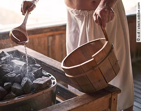 Mann macht einen Aufguss in der Sauna.