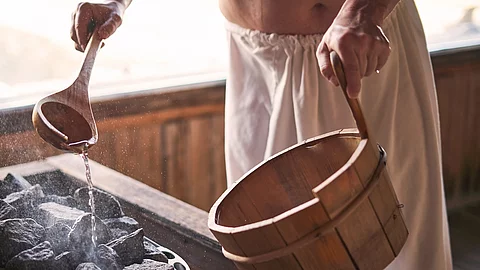 Mann macht einen Aufguss in der Sauna.