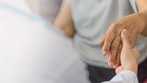 Ärztin hält die Hand einer älteren Patientin