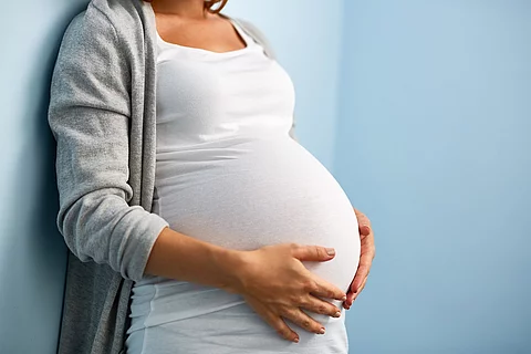 Schwangere Frau hält ihren Bauch.