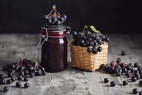 frische Aroniabeeren in Bastkorb, Aroniabeermus im Weckglas