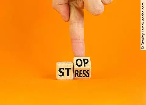 Stress stoppen. Würfel mit den Worten Stop und Stress vor orangefarbenem Hintergrund.