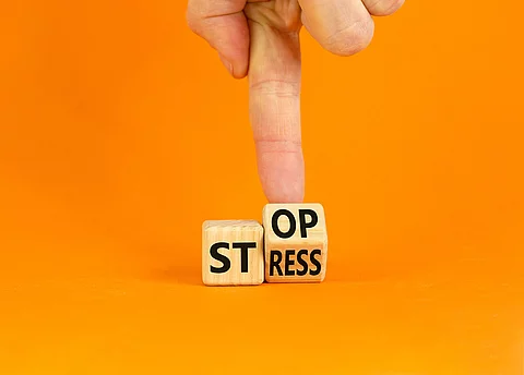 Stress stoppen. Würfel mit den Worten Stop und Stress vor orangefarbenem Hintergrund.