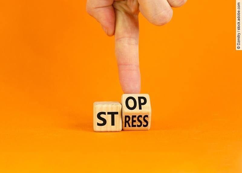 Stress stoppen. Würfel mit den Worten Stop und Stress vor orangefarbenem Hintergrund.