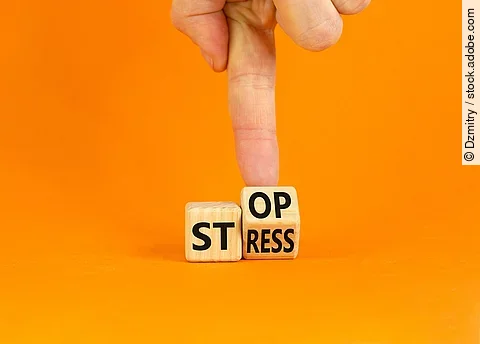 Stress stoppen. Würfel mit den Worten Stop und Stress vor orangefarbenem Hintergrund.