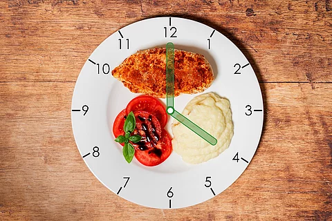 Ein Teller mit Uhrenzifferblatt, darauf Hähnchenbrust, Kartoffelmus und Tomatensalat