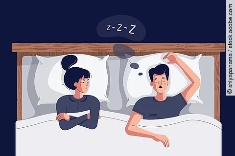 Cartoon-Zeichnung Frau liegt neben schnarchendem Mann im Bett und schaut zornig