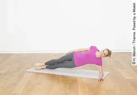 Frau im Seitstütz mit gestreckten Beinen auf der Matte