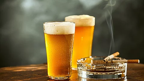 Auf einem Tisch stehen zwei Gläser Bier und ein Aschenbecher mit Zigaretten. 