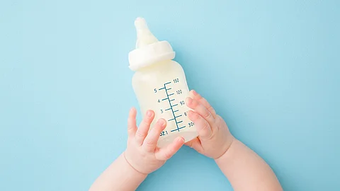 Babyhände halten eine Trinkflasche