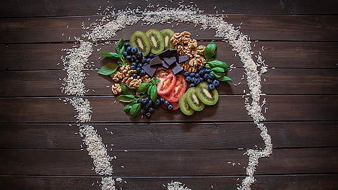 Some nuts, blueberries, dark chocolate, kiwi and tomatoes that are healthy foods for you body and your brain. Nüsse, Beeren, Kiwi, Tomaten in einem mit Kreide gezeichneten Kopf