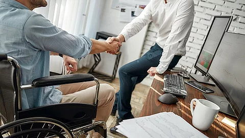 Good deal. Cropped view of male office worker in a wheelchair sh 2 Männer im Büro geben sich die Hand, Vereinbarung